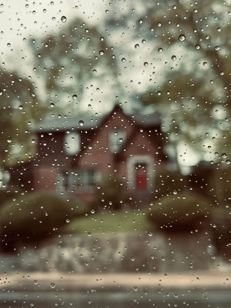 House seen through a rain-covered window during a storm